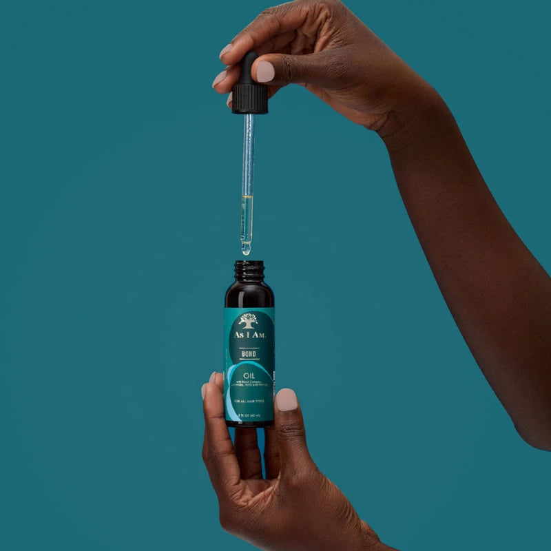 Huile hydratante et fortifiante de As I Am Bond, enrichie en Céramides, Amla et Moringa est formulée pour soigner les cheveux abîmés et secs.